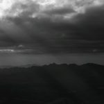Montanhas de Minas Gerais sob nuvens densas e dramáticas, em uma paisagem em preto e branco.