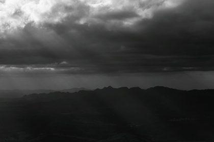 Montanhas de Minas Gerais sob nuvens densas e dramáticas, em uma paisagem em preto e branco.