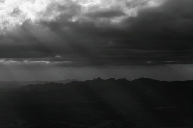 Montanhas de Minas Gerais sob nuvens densas e dramáticas, em uma paisagem em preto e branco.
