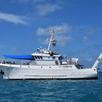 Embarcação de pesquisa La Curieuse navegando em mar aberto sob céu claro.