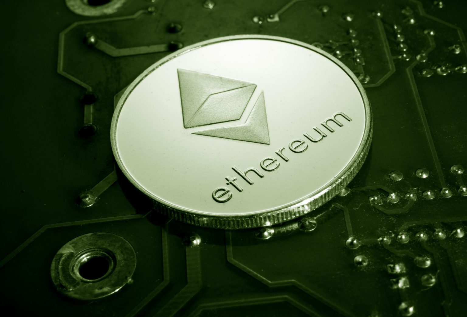 Moeda com o símbolo do Ethereum apoiada sobre uma placa de circuito eletrônico.
