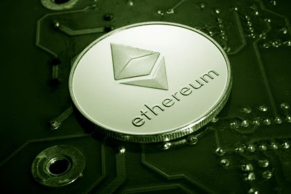 Moeda com o símbolo do Ethereum apoiada sobre uma placa de circuito eletrônico.